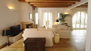 Ein geräumiges Wohnzimmer mit Holzboden, einem Fernseher, einem Sofa, einem Couchtisch und einer Topfpflanze.