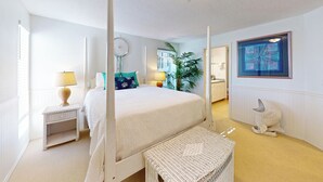 Ein Schlafzimmer mit Himmelbett, Nachttisch inklusive Lampe, eine Bank, einem Wanddekor und Blick auf die Stadt durch das Fenster.