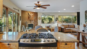 A modern kitchen with a central island, wooden cabinets, and a large window. - Old Western Sonoran Desert Getaway (Cave Creek)