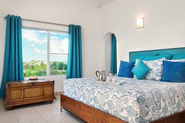 A bedroom with a bed, a nightstand, a window with curtains, and a wall-mounted light fixture.