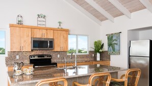 A kitchen with wooden cabinets, a stainless steel refrigerator, and a large island with chairs.
