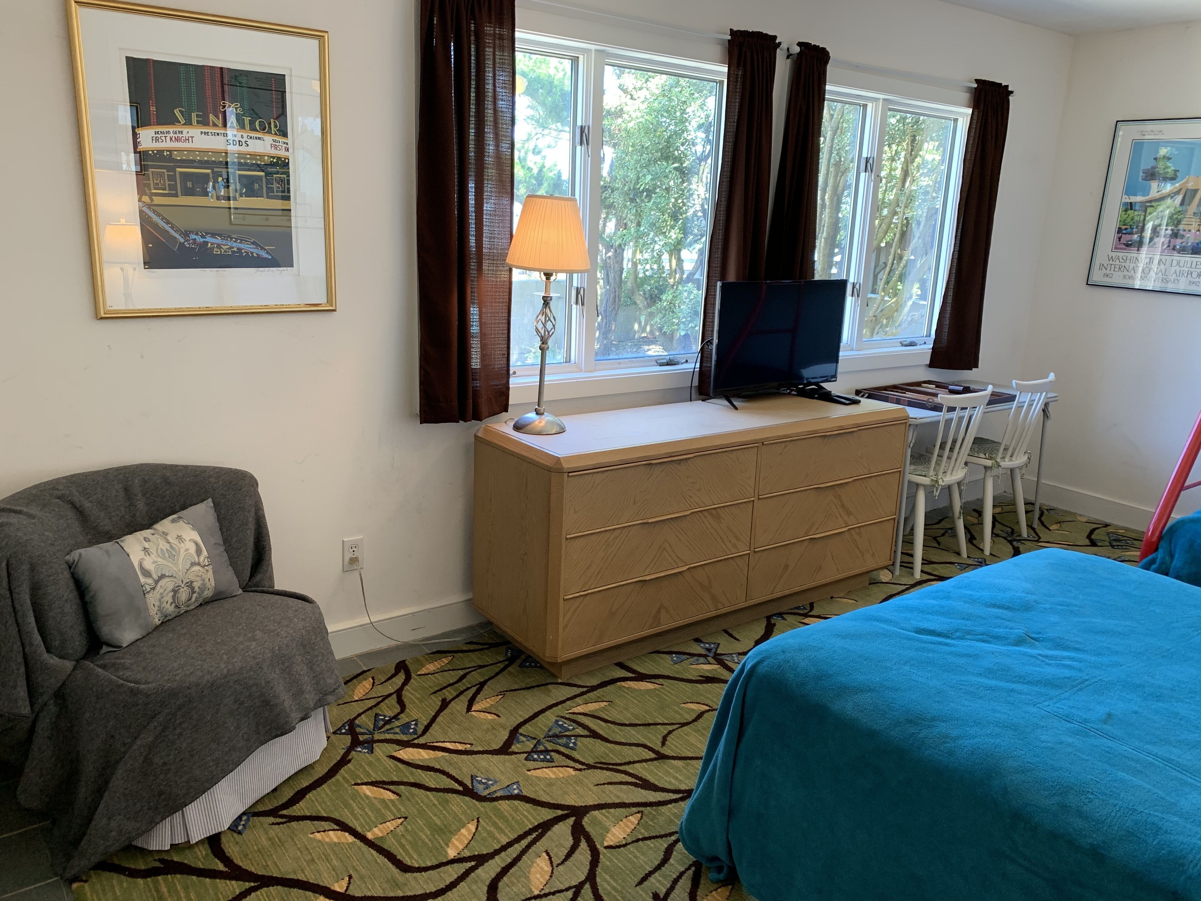 Una habitación de hotel con una cama, un escritorio con televisor, una silla y un sofá.