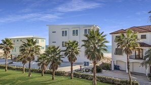A modern building with a flat roof, surrounded by palm trees and a clear blue sky. - Spacious Beachside Condo (Orange Beach)