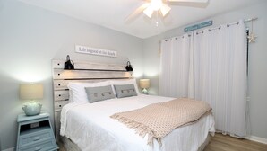 A bedroom with a bed, two bedside tables, a ceiling fan, and a window with curtains. - Spacious Beachside Condo (Orange Beach)