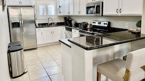 A modern kitchen with white cabinetry, stainless steel appliances, and a granite countertop.
