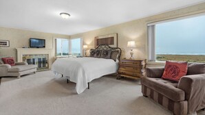 A bedroom with a bed, a dresser, a chair, a television, and a large window with a view. - OCEAN FRONT: PACIFIC HAVEN:  On the Prom: Seaside Vacation Homes, Inc Managed  (Seaside)