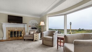 A living room with a fireplace, a sofa, a chair, and a large window offering a view. - OCEAN FRONT: PACIFIC HAVEN:  On the Prom: Seaside Vacation Homes, Inc Managed  (Seaside)