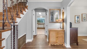 A hallway with a wooden staircase, a wooden cabinet, and a mirror on the wall. - OCEAN FRONT: PACIFIC HAVEN:  On the Prom: Seaside Vacation Homes, Inc Managed  (Seaside)