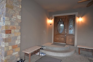 Welcome to a serene entrance area with a wooden door, glass panel, and a cozy bench for resting.