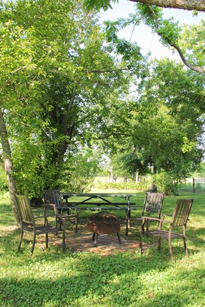 A picnic table with chairs in a grassy area surrounded by trees. - Come Live on the farm (Starke)
