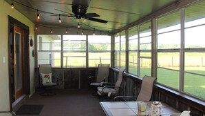 A room with a ceiling fan, string lights, and large windows offering a view of a grassy field. - Come Live on the farm  (Starke)