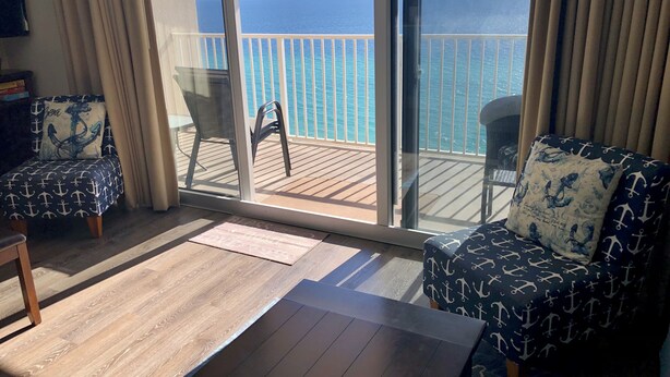 Varanda com vista para o oceano, equipada com duas cadeiras e uma mesa pequena.