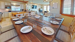 Una cocina amplia con electrodomésticos modernos y una gran mesa de comedor preparada para seis personas.