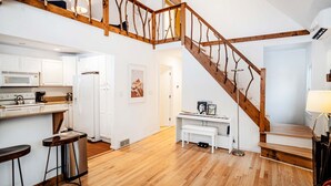 A spacious kitchen with white cabinets, a wooden staircase, and a dining area with a bench. - Beautiful lake house getaway (Pine Bush)