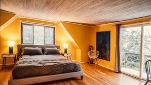 A bedroom with a bed, two bedside tables, a chair, a painting, and a large window. - Beautiful lake house getaway (Pine Bush)