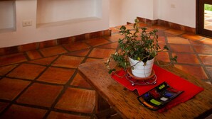 Een kamer met een houten plafond, een bank, een tafel met een bloempot en een rode placemat.