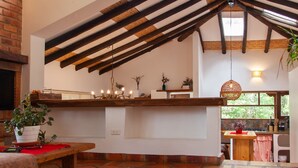 Een ruime keuken met een hoge plafond, zichtbare houten balken en grote ramen voor natuurlijk licht.