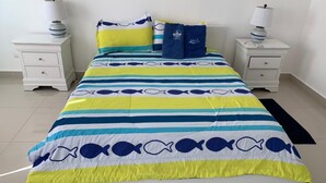 Una cama con una colcha a rayas, dos mesitas de noche y lámparas.