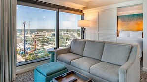 Een hotelkamer met een groot raam, een bank, een nachtkastje en een bed.