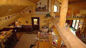 L’intérieur d’un chalet en bois à plusieurs niveaux comprend un coin repas, un escalier et une chambre en mezzanine.