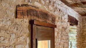 Un muro de piedra con una puerta de madera y un pequeño ventanal con una planta.