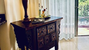 A room with a wooden cabinet, a lamp, and a window with curtains.