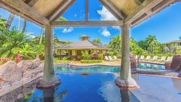 A pool area with lounge chairs and a gazebo.