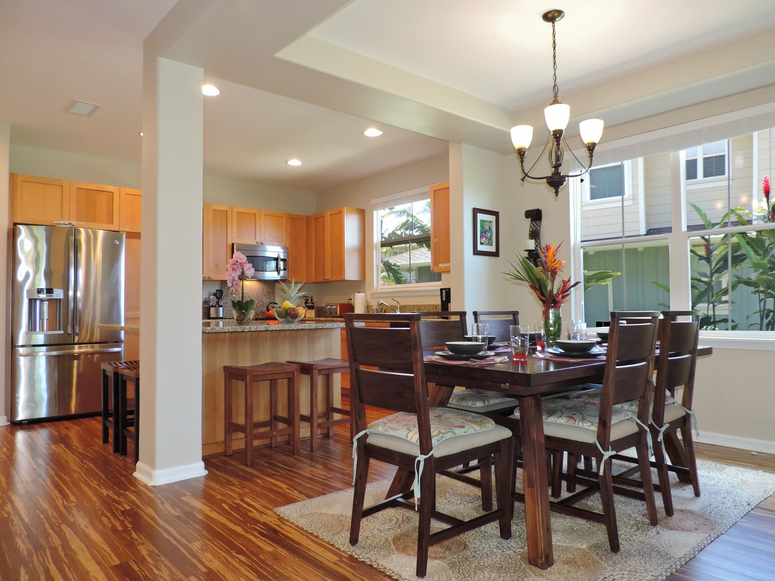A modern kitchen with wooden cabinets, stainless steel appliances, and a dining area with a chandelier.