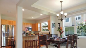 A modern kitchen with wooden cabinets, stainless steel appliances, and a dining area with a chandelier.