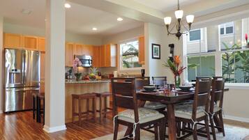 A modern kitchen with wooden cabinets, stainless steel appliances, and a dining area with a chandelier.