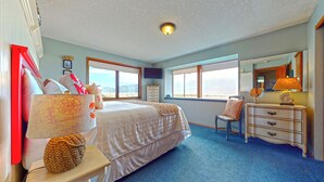 A bedroom with a large bed, a dresser, a chair, and a window with a view. - OCEAN FRONT: BEACHTOPIA South:  Seaside Vacation Homes, Inc Managed  (Seaside)