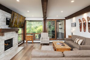 A modern living room with a fireplace, large windows, a sofa, a coffee table, and a chair.