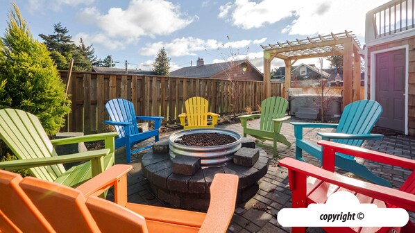 Un patio con sillas Adirondack de colores dispuestas alrededor de un brasero.