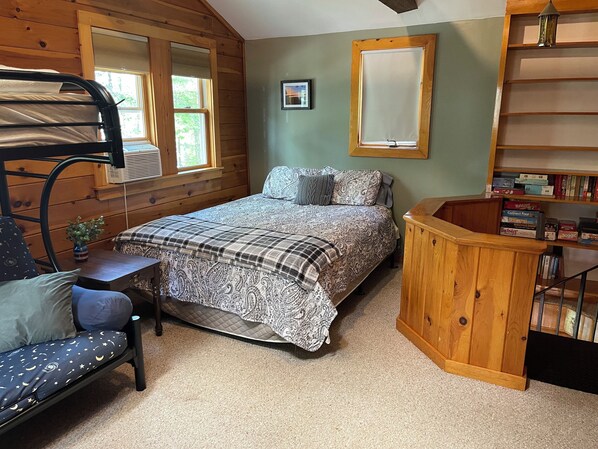 A cozy room with a bunk bed, a desk with a chair, a bookshelf, and a window with blinds. - Sebago Basin Lakehouse School Year Rental (Windham)