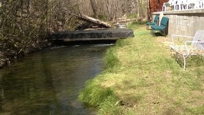 A river with a bridge, grassy banks, and a wall with chairs. - On the river,Close to Midtown,Fun Trackers, The Inn , Fishing. Sleeps 11 in bed (Ruidoso)
