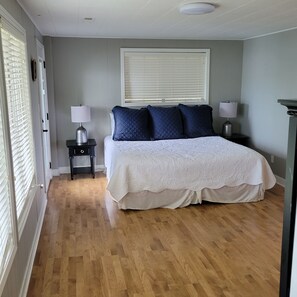 A bedroom with a large bed, two bedside tables, a window with blinds, and a wooden floor. - NEWLY UPDATED!!!Amazing lakefront home (Gravois Mills)