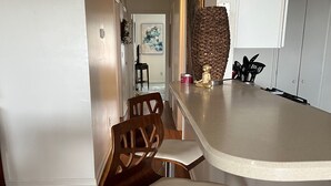 Une cuisine avec un coin bar, des chaises en bois et un comptoir blanc.