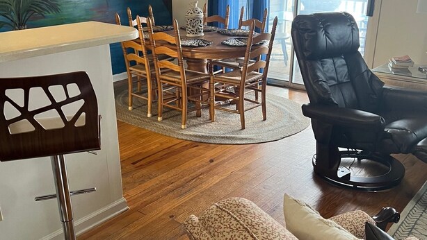 Un coin repas avec une table et des chaises en bois, un tableau accroché au mur et une vue par la fenêtre.