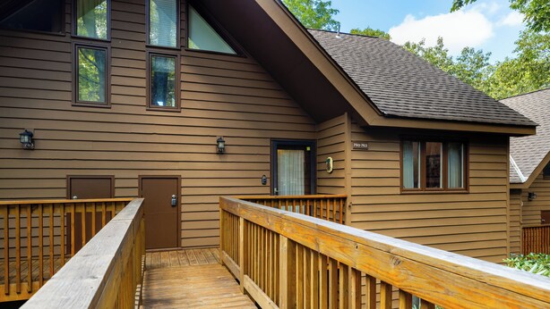 A two-story wooden cabin with a wooden deck and a small porch.