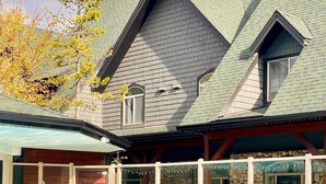 A poolside area with a clear view of a building with a stone facade and a green roof. - Mountain View Chalet - Large Outdoor Pool and Hot tub - Pet Friendly (Canmore)