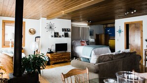 Une pièce confortable avec un lit, un plafond en bois, un ventilateur, une télévision et une plante.