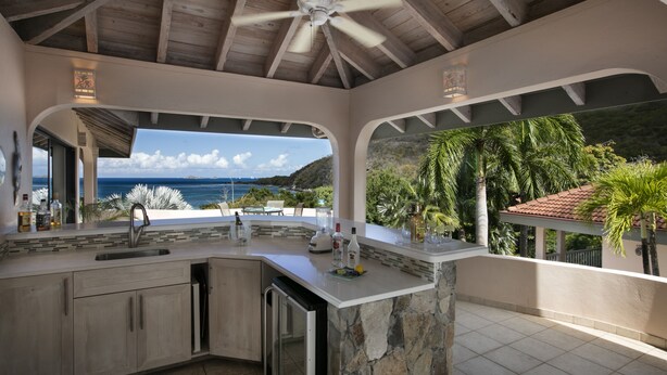 Una cocina moderna con una isla de piedra, lavavajillas integrado y vistas al océano.