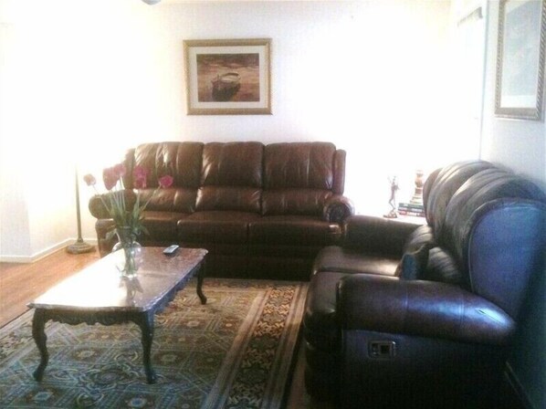A living room with a brown leather sofa, a coffee table, and a rug.