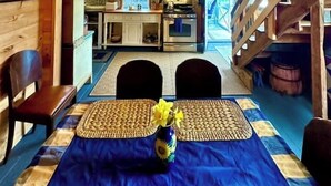 A rustic wooden interior with a dining area featuring a blue tablecloth, a vase with flowers, and a chandelier. - Barn at Blue Hill Peninsula Historic farm w/Organic Meadows. Pet friendly (Brooksville)