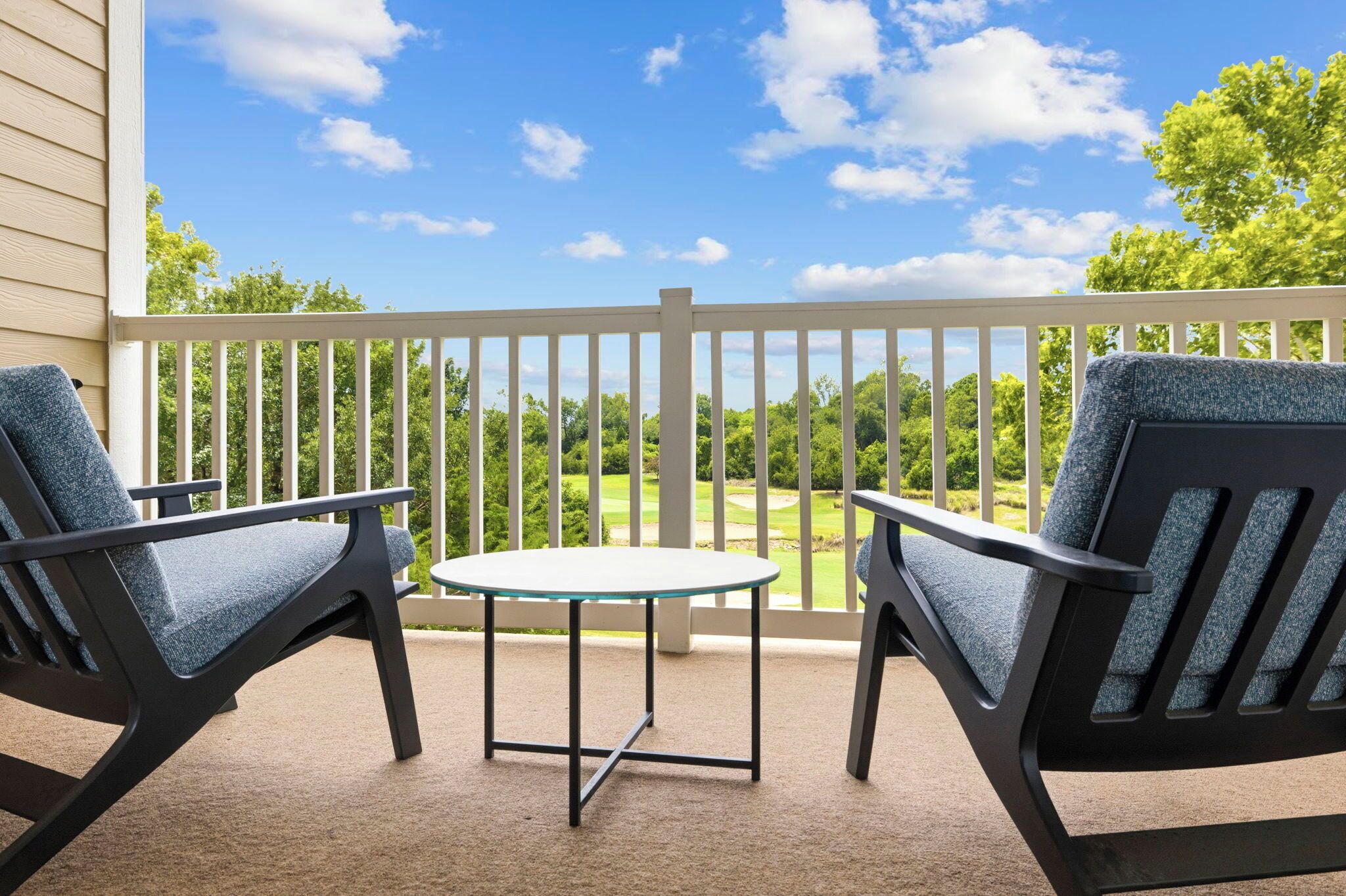 A balcony with two chairs and a small table, overlooking a green landscape.