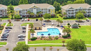 A multi-story hotel with a swimming pool surrounded by lounge chairs and umbrellas.
