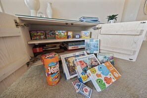 Une pièce dans laquelle se trouve un meuble en bois contenant des jeux de société et des jeux de réflexion.