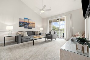 A modern living room with a sofa, armchairs, a coffee table, and a glass-top desk.