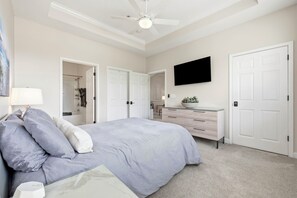 Une chambre à coucher avec un lit, une commode, un téléviseur et un ventilateur de plafond.