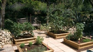 A garden with raised beds, a wooden bench, and a stone wall. - Country Villa 'Mas' in the Heart of Provence, 4bed, 4bath with AC (Rognonas)